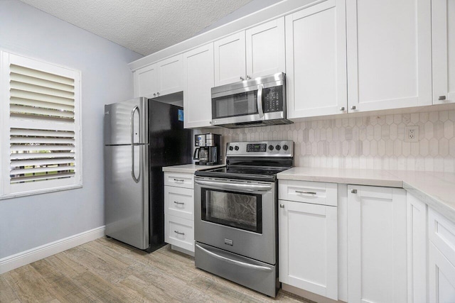 kitchen featuring white cabinetry, light wood-type flooring, a textured ceiling, appliances with stainless steel finishes, and decorative backsplash