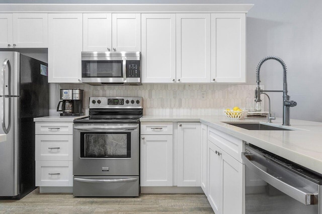 kitchen featuring sink, light hardwood / wood-style flooring, white cabinets, and stainless steel appliances