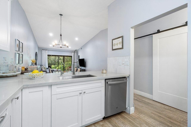 kitchen featuring vaulted ceiling, light hardwood / wood-style floors, a barn door, white cabinetry, and dishwasher