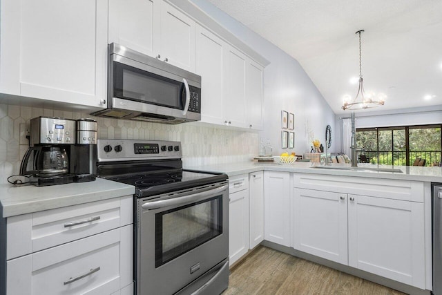 kitchen with stainless steel appliances, an inviting chandelier, backsplash, light wood-type flooring, and lofted ceiling