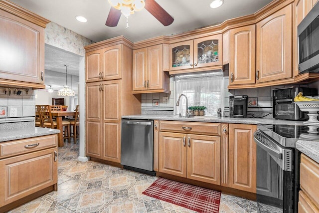 kitchen featuring decorative backsplash, ceiling fan, appliances with stainless steel finishes, hanging light fixtures, and sink