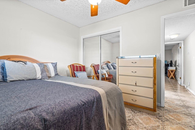 bedroom featuring ceiling fan, light tile patterned flooring, a textured ceiling, and a closet