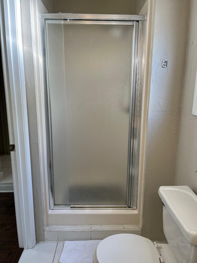 bathroom featuring an enclosed shower, hardwood / wood-style flooring, and toilet