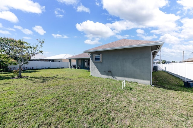 rear view of property with a shingled roof, a lawn, a fenced backyard, and stucco siding