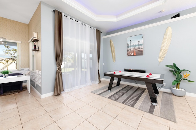 recreation room featuring a tray ceiling, light tile patterned flooring, crown molding, wallpapered walls, and baseboards