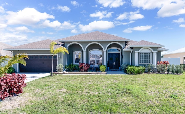 view of front facade featuring stucco siding, driveway, a front yard, and a garage