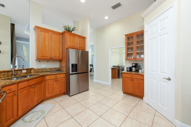 kitchen featuring stone counters, sink, light tile patterned flooring, and stainless steel fridge with ice dispenser