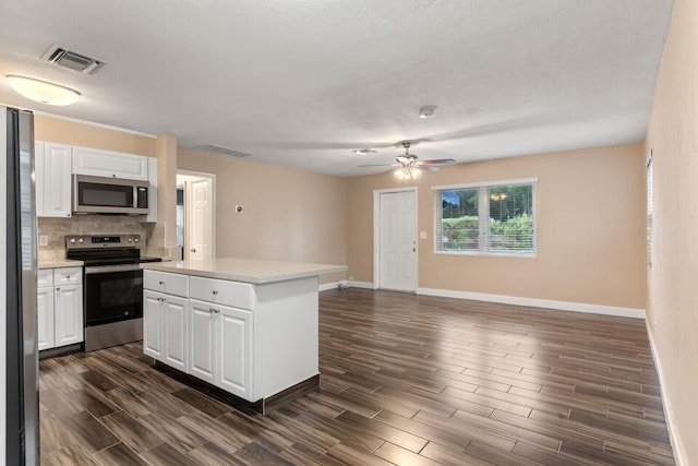 kitchen featuring white cabinets, decorative backsplash, a center island, ceiling fan, and stainless steel appliances