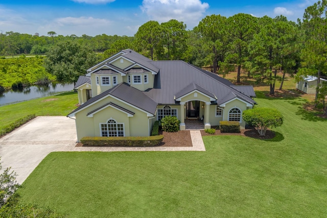 view of front of home featuring stucco siding, driveway, metal roof, and a front yard