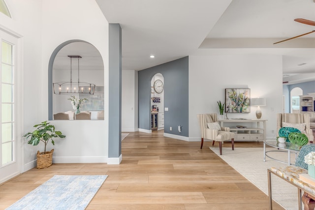 entryway featuring light hardwood / wood-style flooring and ceiling fan with notable chandelier