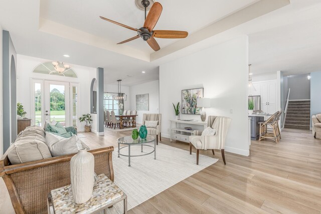 living area featuring recessed lighting, baseboards, stairway, light wood-type flooring, and a raised ceiling