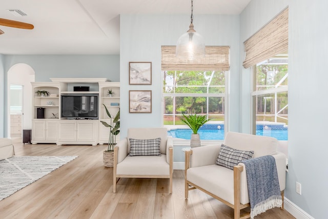 sitting room with visible vents, baseboards, arched walkways, and wood finished floors