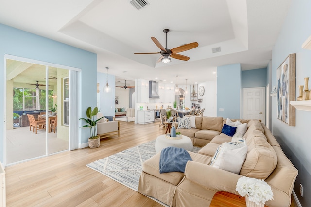 living room with a raised ceiling and light hardwood / wood-style floors