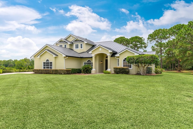 view of front facade featuring a standing seam roof, a front lawn, stucco siding, and metal roof