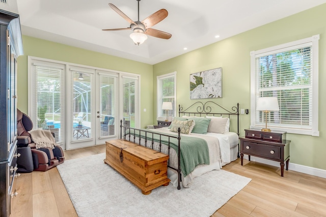 bedroom featuring recessed lighting, baseboards, access to exterior, light wood-type flooring, and a tray ceiling