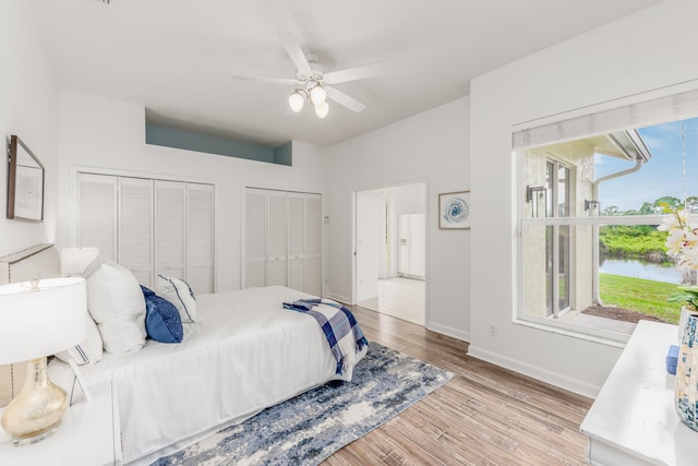 bedroom featuring multiple windows, ceiling fan, light hardwood / wood-style flooring, and a water view