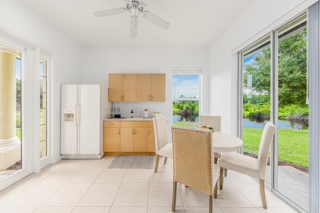 dining room featuring a water view, light tile patterned floors, and ceiling fan