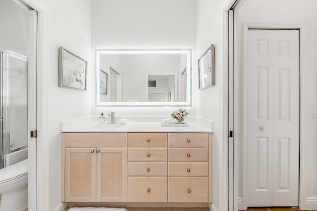 bathroom featuring toilet, enclosed tub / shower combo, a closet, and vanity