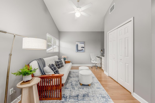 living room with visible vents, light wood-style flooring, ceiling fan, high vaulted ceiling, and baseboards