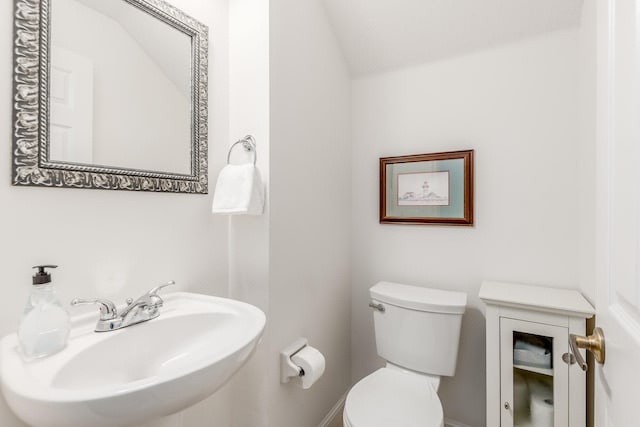 bathroom with toilet, sink, and vaulted ceiling