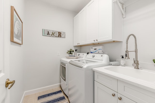 clothes washing area with baseboards, a sink, cabinet space, and washer and dryer