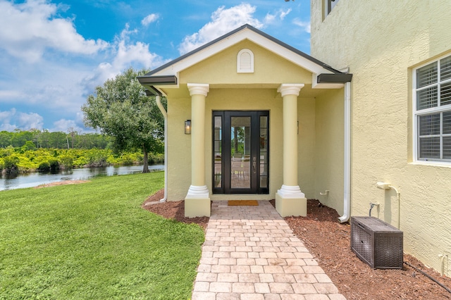 entrance to property featuring a lawn and a water view