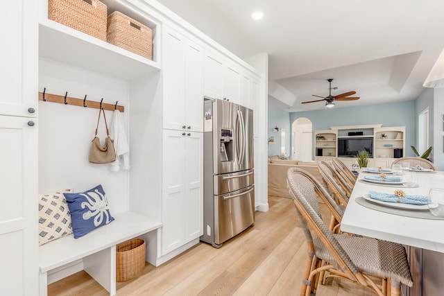 dining space with ceiling fan, light wood-type flooring, and a tray ceiling