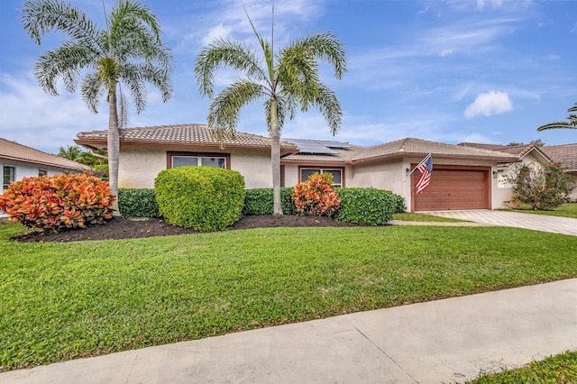 view of front of home with a garage, a front yard, and solar panels