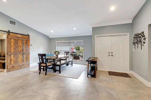 dining room featuring crown molding, a barn door, vaulted ceiling, and light tile patterned floors