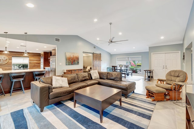 living room featuring light tile patterned flooring, vaulted ceiling, ornamental molding, ceiling fan, and a barn door