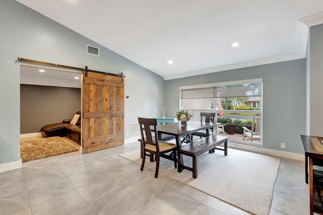 dining area featuring lofted ceiling, ornamental molding, and a barn door