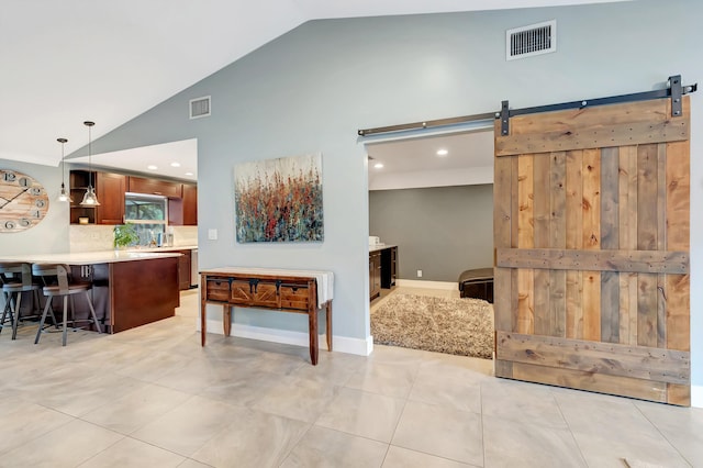 kitchen with a kitchen bar, tasteful backsplash, hanging light fixtures, light tile patterned floors, and a barn door