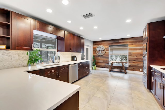 kitchen featuring a healthy amount of sunlight, appliances with stainless steel finishes, wooden walls, and sink