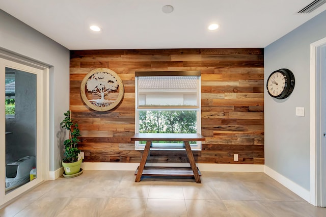 unfurnished dining area featuring tile patterned flooring and wooden walls