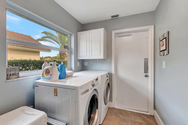 laundry area featuring washer and dryer, light tile patterned floors, and cabinets