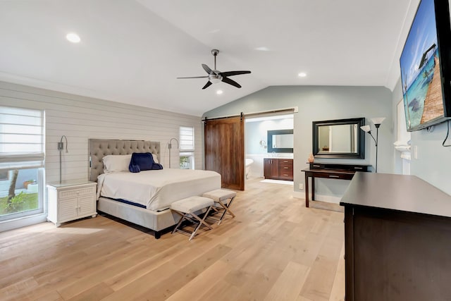 bedroom with lofted ceiling, ensuite bathroom, ceiling fan, a barn door, and light hardwood / wood-style floors