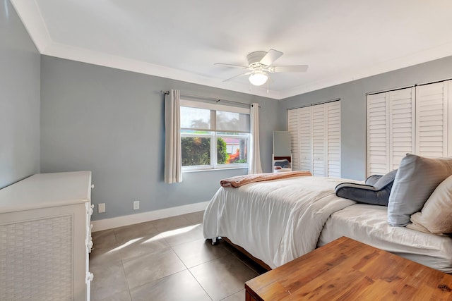 tiled bedroom featuring ceiling fan, ornamental molding, and multiple closets