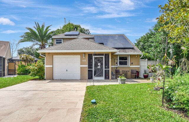 view of front facade featuring a garage, solar panels, and a front yard