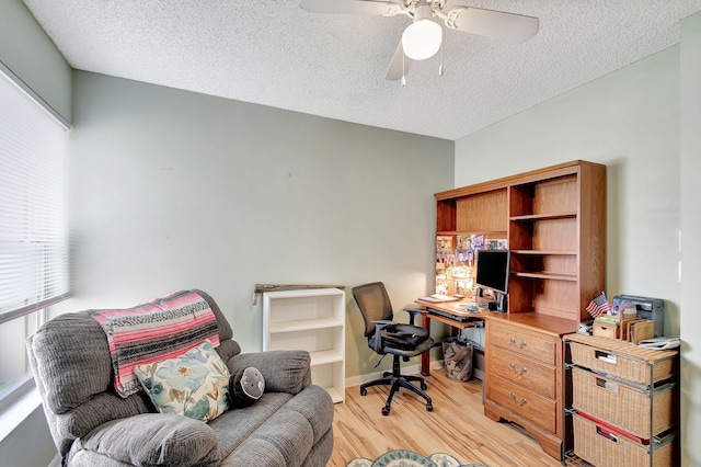 office space with ceiling fan, a textured ceiling, and light wood-type flooring