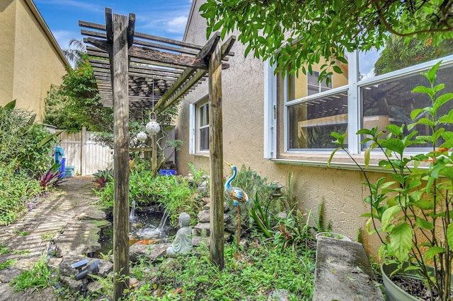 view of side of property featuring a pergola, fence, and stucco siding