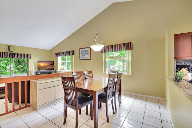 tiled dining space featuring a stone fireplace and high vaulted ceiling