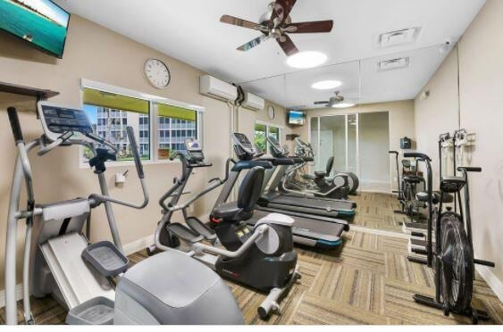 exercise room with ceiling fan, carpet flooring, and a wall mounted air conditioner