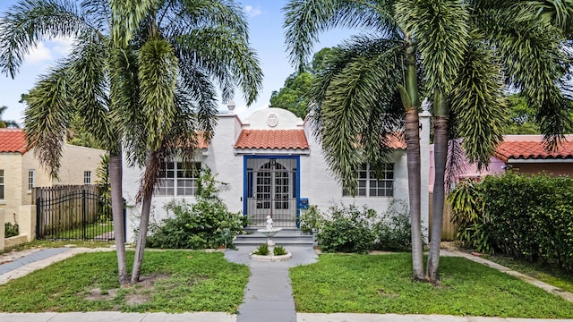 435 35th St, West Palm Beach, FL 33407 - mediterranean / spanish-style home featuring fence, a front lawn, stucco siding, and a tile roof