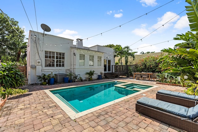 view of pool featuring an in ground hot tub, cooling unit, and a patio area