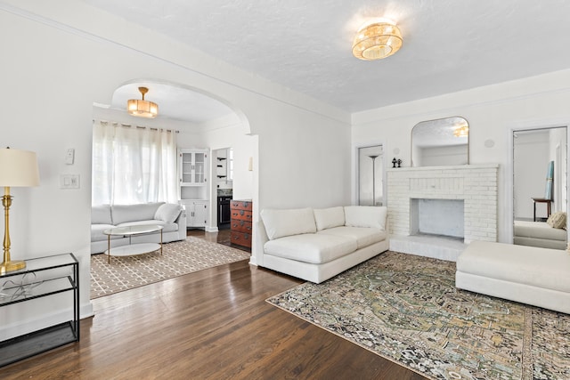 living room featuring a brick fireplace, hardwood / wood-style floors, and a textured ceiling