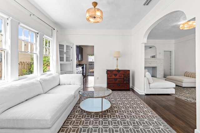 living room featuring a brick fireplace and dark hardwood / wood-style floors