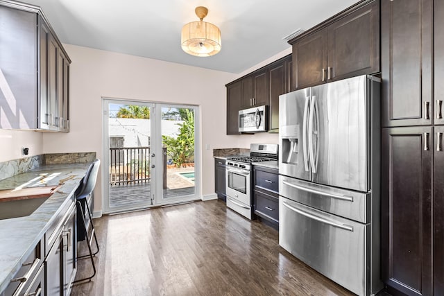 435 35th St, West Palm Beach, FL 33407 - kitchen featuring appliances with stainless steel finishes, light stone counters, baseboards, dark brown cabinets, and dark wood finished floors