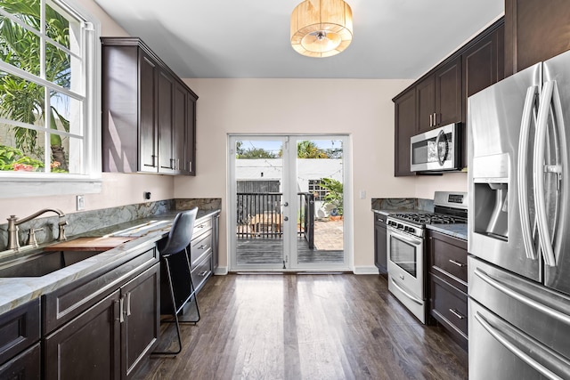 435 35th St, West Palm Beach, FL 33407 - kitchen with dark brown cabinetry, light stone counters, stainless steel appliances, dark wood-style floors, and french doors