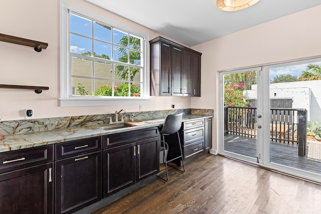 kitchen featuring light stone countertops, a wealth of natural light, sink, and dark hardwood / wood-style floors