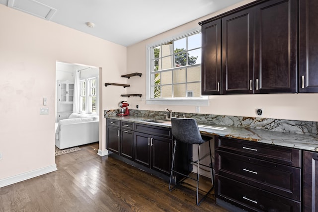 435 35th St, West Palm Beach, FL 33407 - kitchen with dark brown cabinetry, light stone counters, a sink, baseboards, and dark wood-type flooring